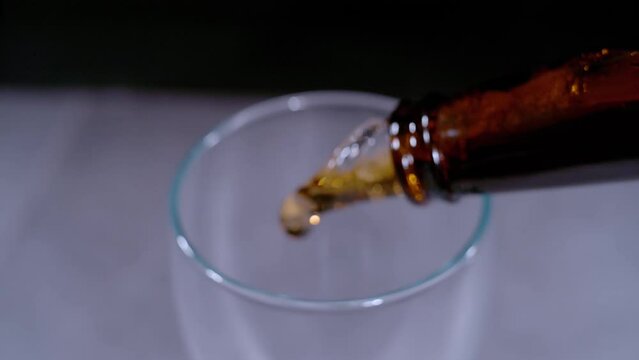 SUPER SLOW MOTION, CLOSE UP: Detailed view of pouring fresh cold beer from bottle into the beer glass. Gentle liquid movement while pouring beverage from bottle to glass. Refreshment for summer days.