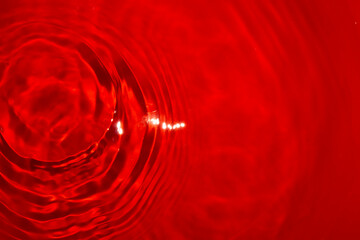 calm red water and a drop that made rings in the left corner of the abstract water background,...