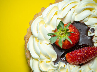 Cake with butter cream and strawberries. Cake on a yellow background. Treat for tea.