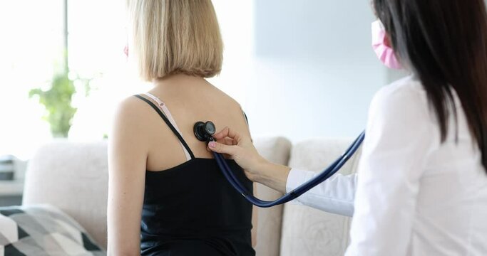 Doctor listens to patient lungs from back at home