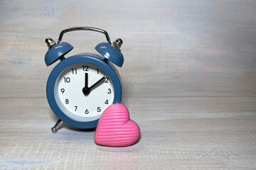 Pink heart near the blue alarm clock. Love time