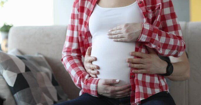 Man and woman are stroking belly in last month of pregnancy