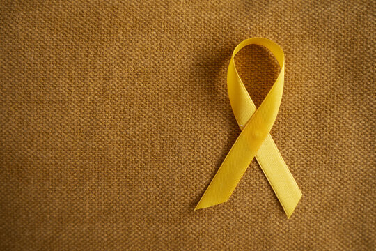 Yellow ribbon on brown background, emblem for suicide prevention awareness, particularly for young people