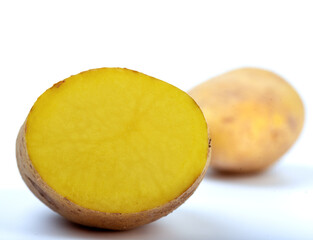 A cut ripe potato and a blurred whole in the background.