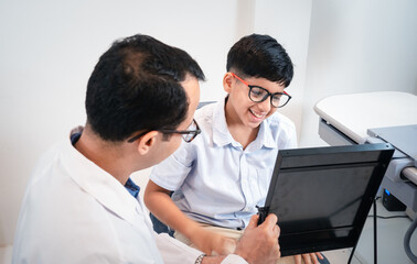 Happy Indian father and cute son choosing eyeglasses in an optics store..