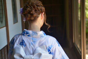 縁側でたたずむ浴衣を着た若い女性の後ろ姿