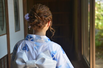 縁側でたたずむ浴衣を着た若い女性の後ろ姿	