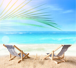Vacation holidays background concept - two beach lounge chairs under palm on summer beach.