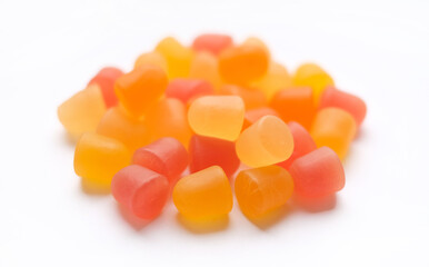 Close-up texture of orange and yellow multivitamin gummies in the form of bears on white...