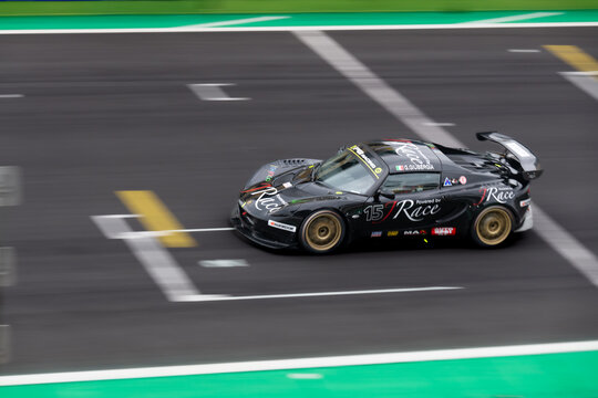 Racing car crossing finish line on asphalt main straight racetrack, Lotus Elise blurred motion background