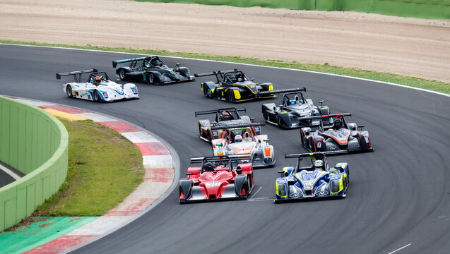 Large group of racing cars challenging at turn on asphalt racetrack