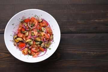Salad with mussels and tomatoes and red onion in white plate on wooden table. Concept of healthy diet food. Flat lay. Copy space.