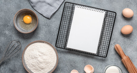 Fototapeta na wymiar Baking ingredients and a blank notepad on a gray concrete background. Top view, flat lay. Banner