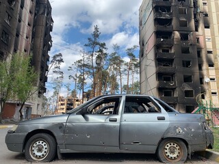 The ruins of the house and traces of shots on the body of the car. A burnt and shelled car against...