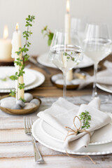 Rustic zero waste wedding decor with natural elements. Wooden table, candles, linen napkins, branches with green leaves. Eco-friendly decoration for the special dinner. Romantic and cozy place