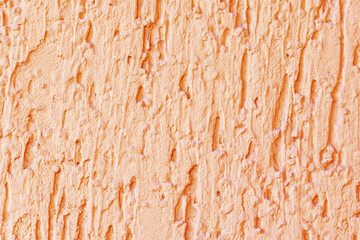 The yellow-pink texture of the plaster of the outer wall of the building is close-up. Deep touches in the plaster.