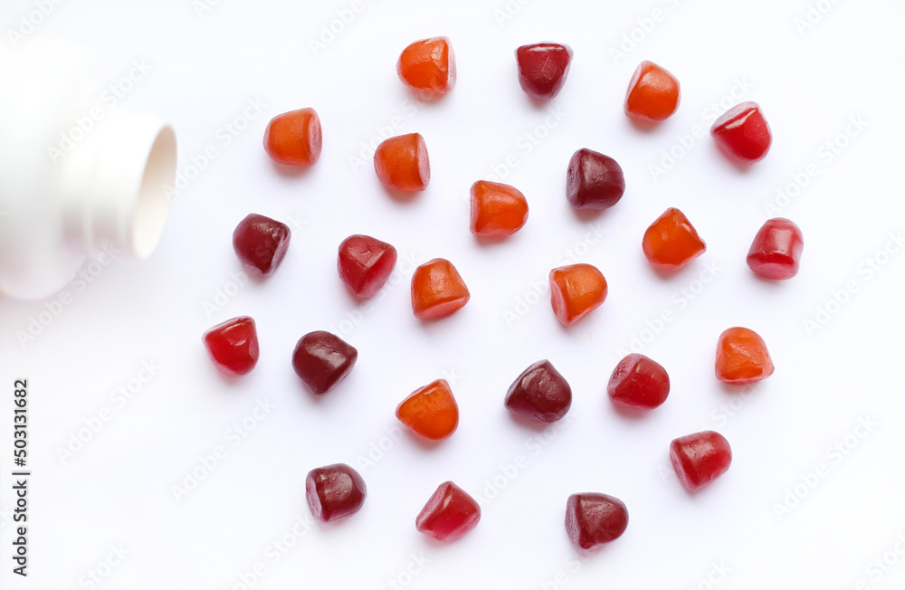 Wall mural group of red, orange and purple multivitamin gummies with the bottle isolated on white background.