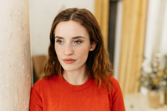 Young woman has red sweater and looks thoughtfully to the side