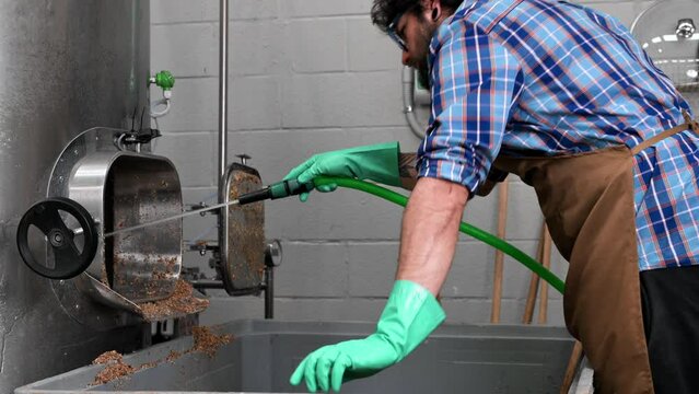 Man working in a brewery, cleaning inside of a large stainless steel kettle with a high pressure washer. High quality 4k footage