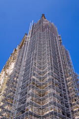 Low-angle shot of a high-rise building with scaffolding against a blue sky on a sunny day