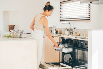 Woman washes dishes in the dishwasher at the kitchen,
