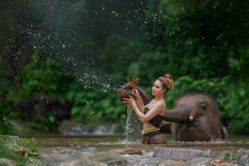 A girl with the elephant in the water.