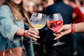 Gardinen Two women holding a gin and tonic and toasting during a music festival © Pablo Gallardo
