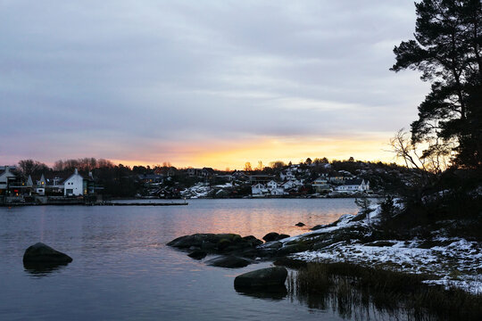 Frozen lake or river covered with snow in the forest in winter in Larvik, Norway at sunset