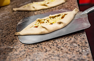 chef baker making pide at kitchen. Put on landing shovel and send it to the oven.