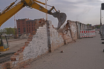 Excavator demolishing a wall on a construction site