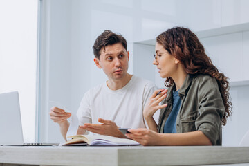 Couple of brunette wife and dark-haired husband holding supermarket check argues gesturing about unplanned family expenses after calculation
