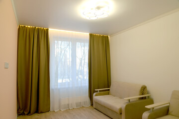 A fragment of the interior of a living room with a ceiling lamp and LED window lighting