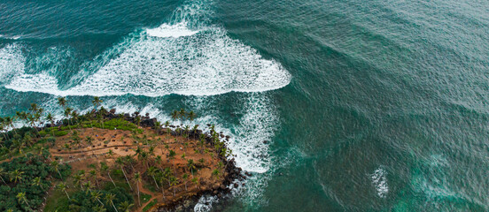 Tropical island with palms, ocean in the background, shot from a drone, top view.