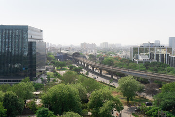 noon shot showing glass covered skyscrapers with offices homes with trees and the elevated metro...