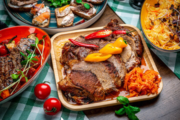 Roasted juicy pork with vegetables on a wooden plate