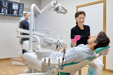 Dentist curing male patient at dental clinic