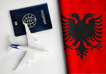 Flag of Albania with passport and toy airplane. Flight travel concept
