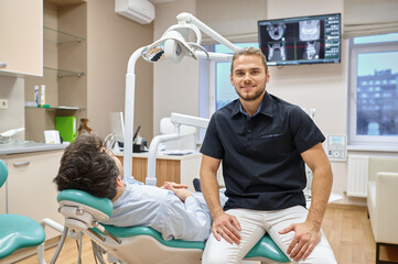 Dentist sitting near patient in chair portrait