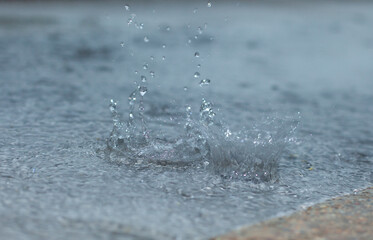 Rain drops on the ground and water splashes. Stationary water distribution.
