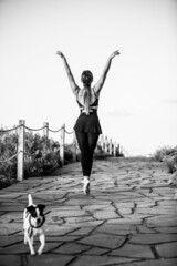 Vertical shot of a ballerina with a neat figure and the Jack Russell terrier in grayscale
