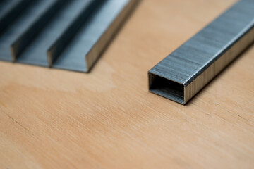 Metal staples for stapler isolated on wooden background - obrazy, fototapety, plakaty