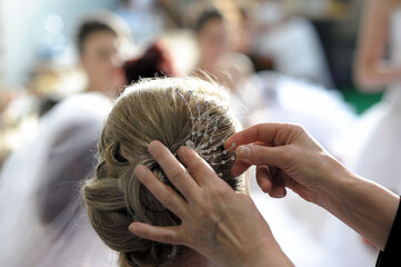 Closeup shot of a stylist placing a hair accessory on a blonde bun