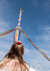 Young dancer looking at the pole with colored ribbons on a traditional English Maypole dancing day