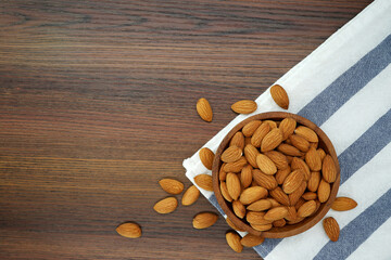 Almonds in bowl on wooden background