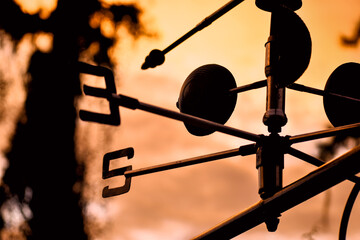 Beautiful silhouette of a weather vane during sunset on the orange sky background - obrazy, fototapety, plakaty