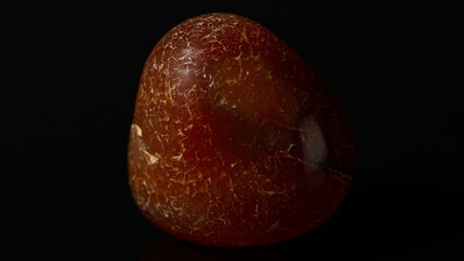 Closeup of a polished Carnelian red agate on a black background