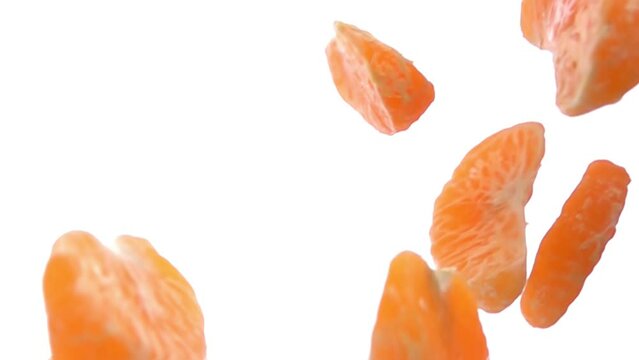 Peeled tangerine pieces are falling and rotating on the white background