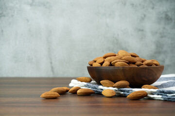 Almonds in bowl on wooden table background