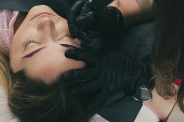 The master of permanent make up performs eyebrow microblading in beauty salon