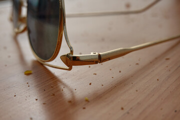 Closeup of golden frame sunglasses on a dirty wooden surface